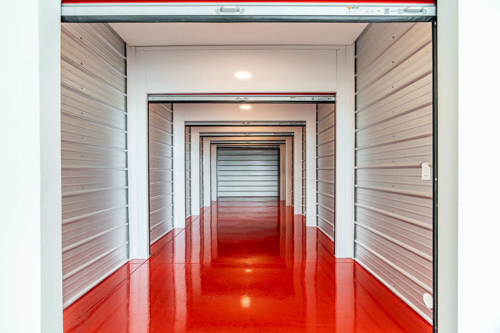 Interior hallway of Modern Storage with bright red floors, illustrating secure, climate-controlled units and insurance options