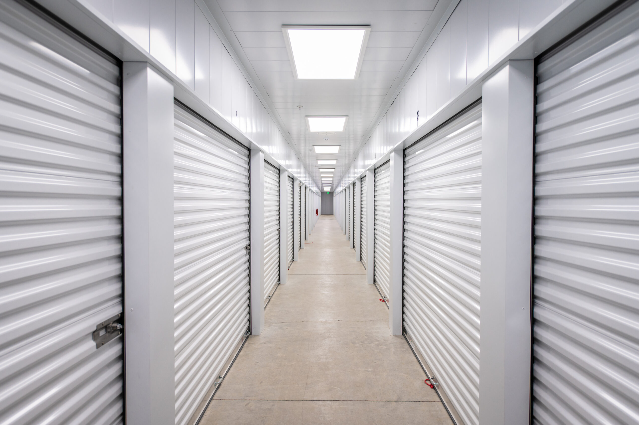 Clean, well-lit indoor hallway with white roll-up storage doors at Modern Storage® facility
