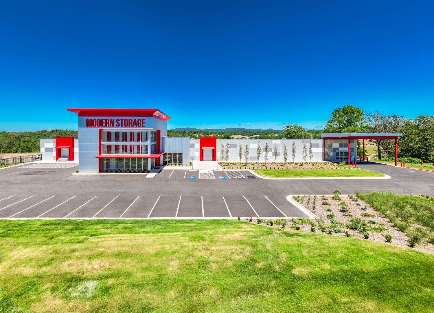 Front view of Modern Storage® facility with red and gray exterior and clear blue sky